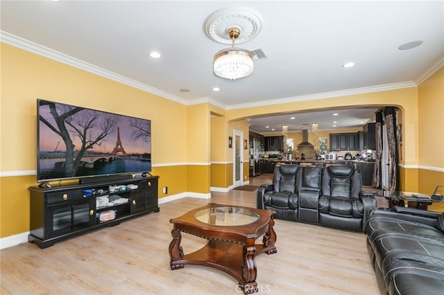 living room featuring a chandelier, ornamental molding, and light hardwood / wood-style flooring