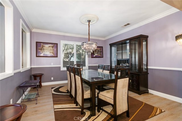 dining area with a chandelier, light hardwood / wood-style floors, and crown molding