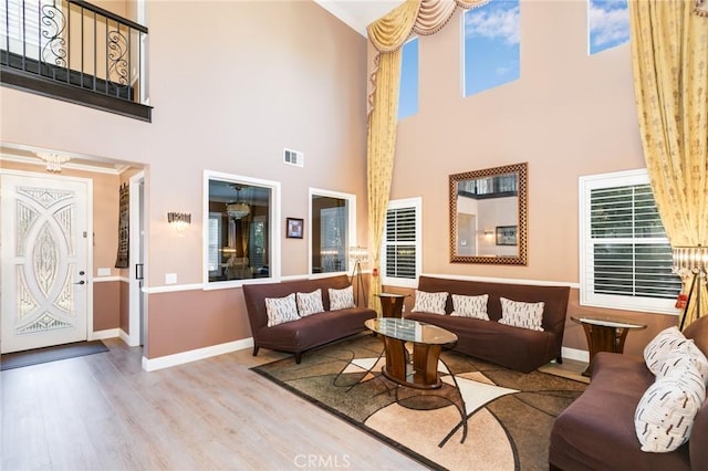 living room with a high ceiling, light hardwood / wood-style floors, and a healthy amount of sunlight