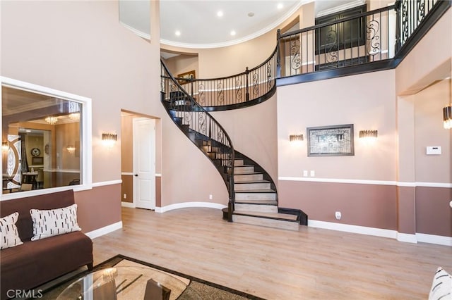 living room featuring hardwood / wood-style floors, a towering ceiling, and ornamental molding