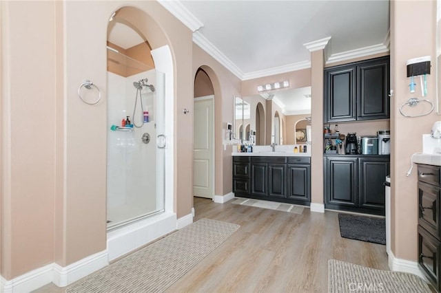 bathroom with hardwood / wood-style flooring, vanity, ornamental molding, and a shower with door