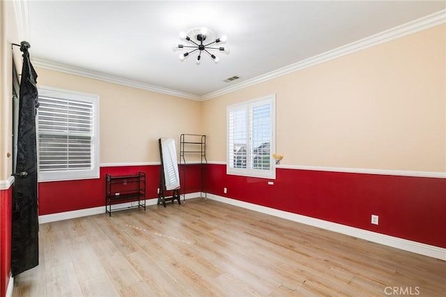 spare room with light wood-type flooring, ornamental molding, and a chandelier