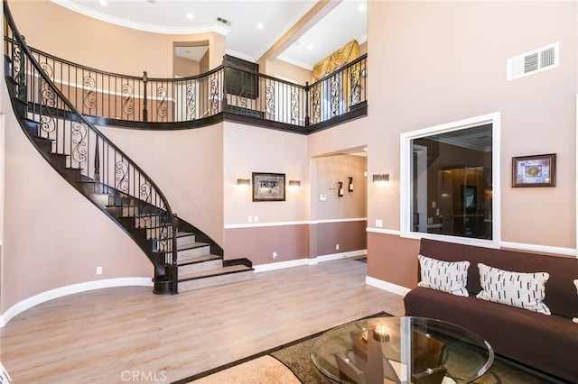 interior space featuring a towering ceiling, hardwood / wood-style flooring, and crown molding