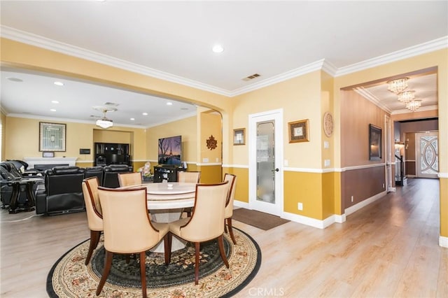 dining room with light hardwood / wood-style flooring, crown molding, and a notable chandelier