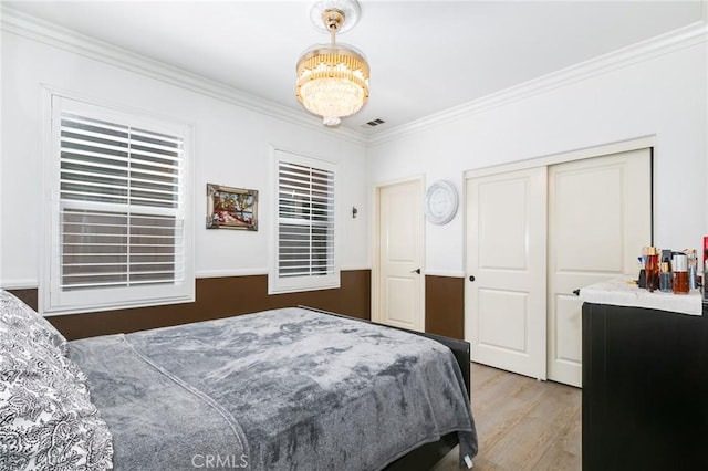 bedroom featuring hardwood / wood-style flooring, a closet, crown molding, and a chandelier