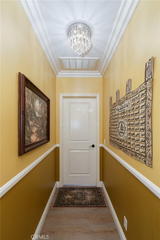 doorway to outside featuring hardwood / wood-style flooring, ornamental molding, and a chandelier