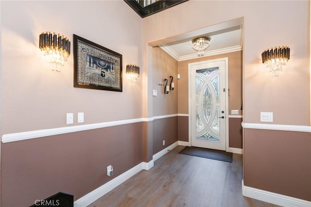 foyer with an inviting chandelier, ornamental molding, and hardwood / wood-style flooring