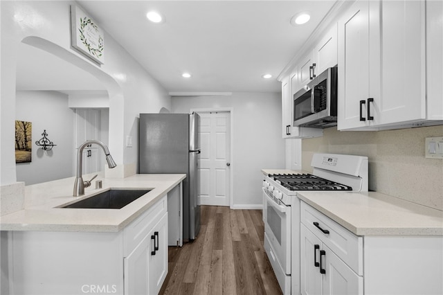 kitchen with hardwood / wood-style floors, white cabinets, sink, and stainless steel appliances