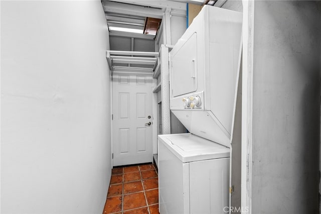 washroom with dark tile patterned flooring and stacked washer and clothes dryer