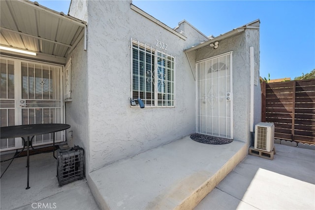 view of exterior entry featuring a patio area and ac unit