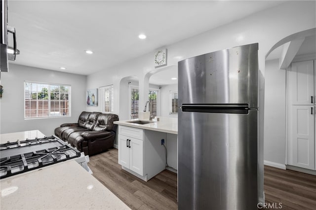 kitchen featuring light stone countertops, stainless steel fridge, sink, hardwood / wood-style floors, and white cabinetry