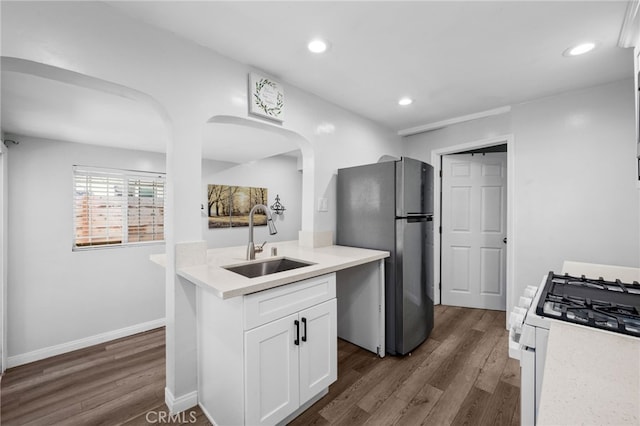 kitchen featuring white cabinets, white gas range oven, sink, dark hardwood / wood-style flooring, and stainless steel refrigerator