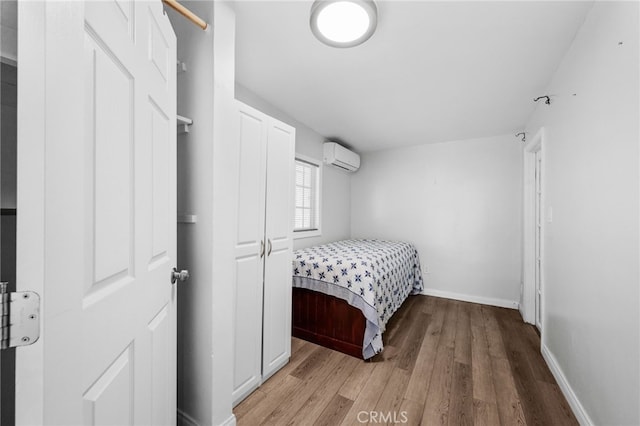 bedroom with a wall mounted air conditioner and light wood-type flooring