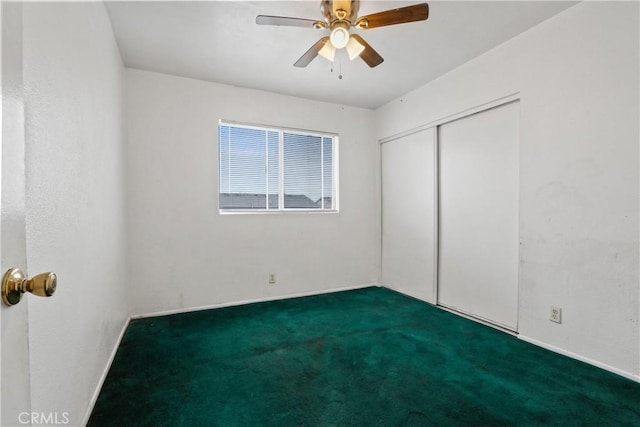 spare room featuring dark carpet and ceiling fan