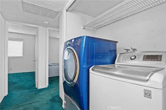 laundry room featuring washing machine and dryer, a textured ceiling, and dark colored carpet