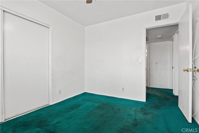 empty room featuring ceiling fan and dark colored carpet