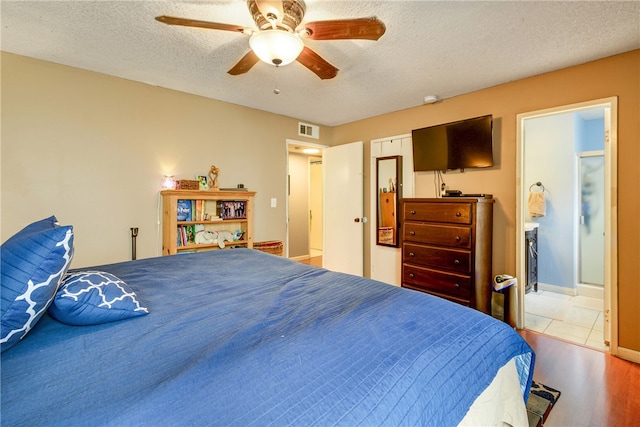 bedroom featuring ensuite bath, hardwood / wood-style flooring, a textured ceiling, and ceiling fan