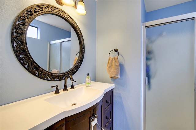 bathroom with a shower with shower door and vanity