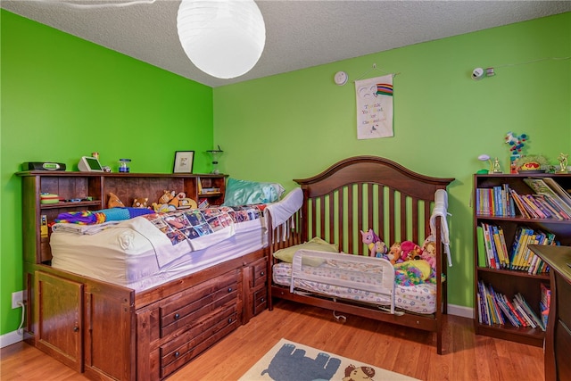 bedroom featuring light hardwood / wood-style flooring and a textured ceiling