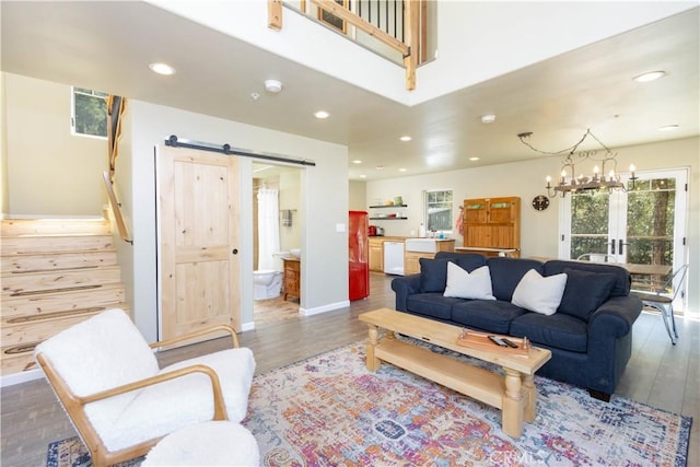 living room with hardwood / wood-style floors, a barn door, french doors, and a notable chandelier