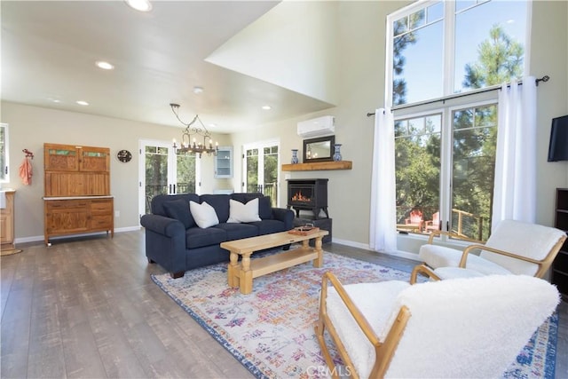 living room featuring dark hardwood / wood-style floors, an inviting chandelier, a wall mounted AC, and a healthy amount of sunlight