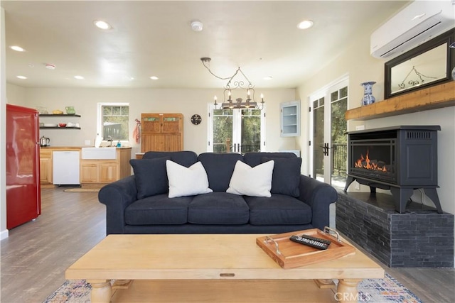 living room featuring an inviting chandelier, french doors, sink, dark hardwood / wood-style floors, and a wall unit AC