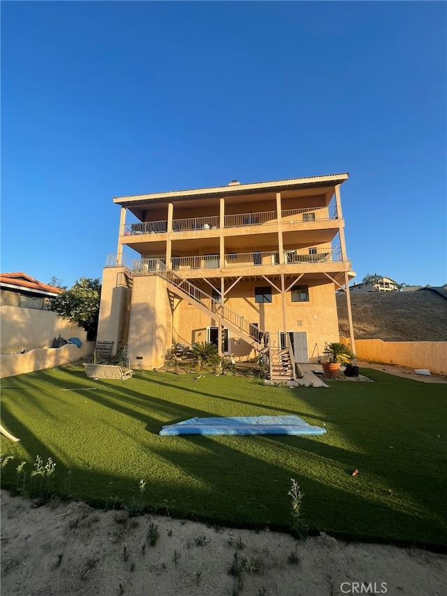 back of house with a balcony and a yard