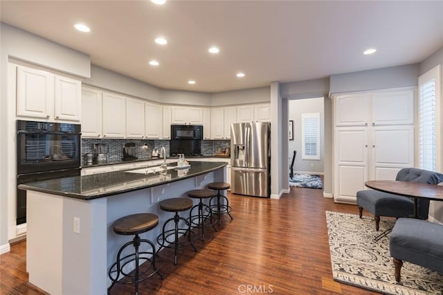 kitchen featuring stainless steel refrigerator with ice dispenser, dark hardwood / wood-style flooring, dark stone counters, white cabinets, and sink