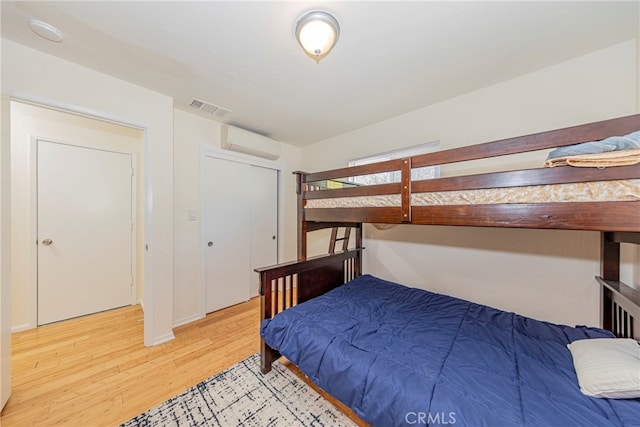 bedroom featuring an AC wall unit and light hardwood / wood-style flooring