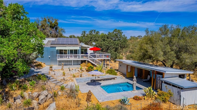 rear view of house with a swimming pool with hot tub, solar panels, and a patio area