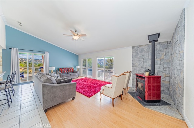 living room with crown molding, hardwood / wood-style floors, a wood stove, and a healthy amount of sunlight