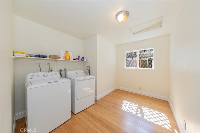 clothes washing area with light wood-type flooring and washer and clothes dryer