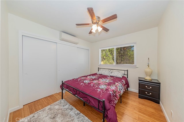 bedroom with a closet, light wood-type flooring, ceiling fan, and a wall mounted AC