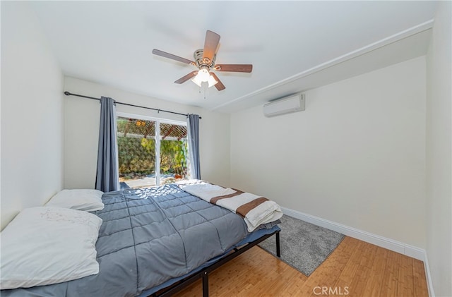 bedroom with an AC wall unit, ceiling fan, and hardwood / wood-style floors