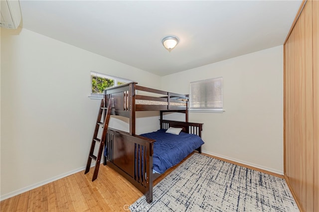 bedroom with light wood-type flooring and a wall mounted AC