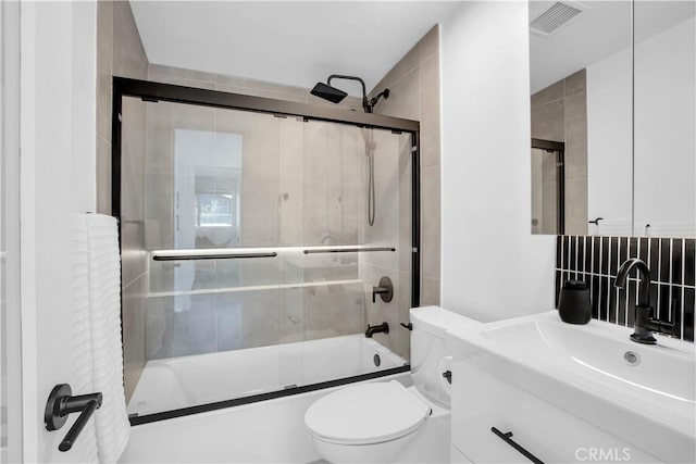 full bathroom with bath / shower combo with glass door, vanity, and toilet