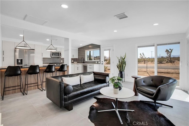 tiled living room featuring a healthy amount of sunlight, lofted ceiling, and sink