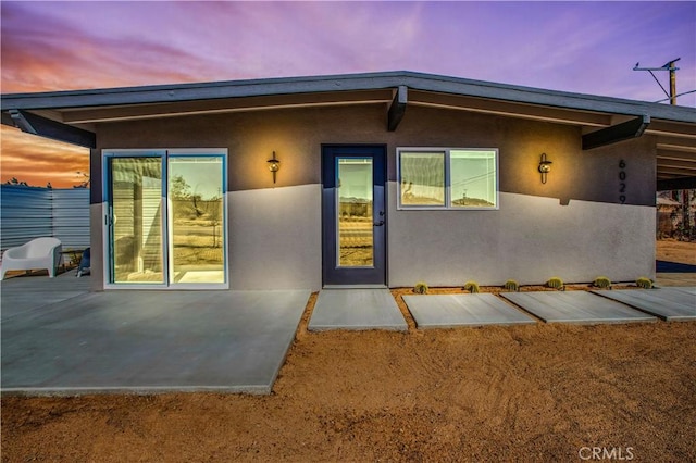 exterior entry at dusk featuring a patio area