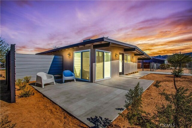 back house at dusk featuring a patio area