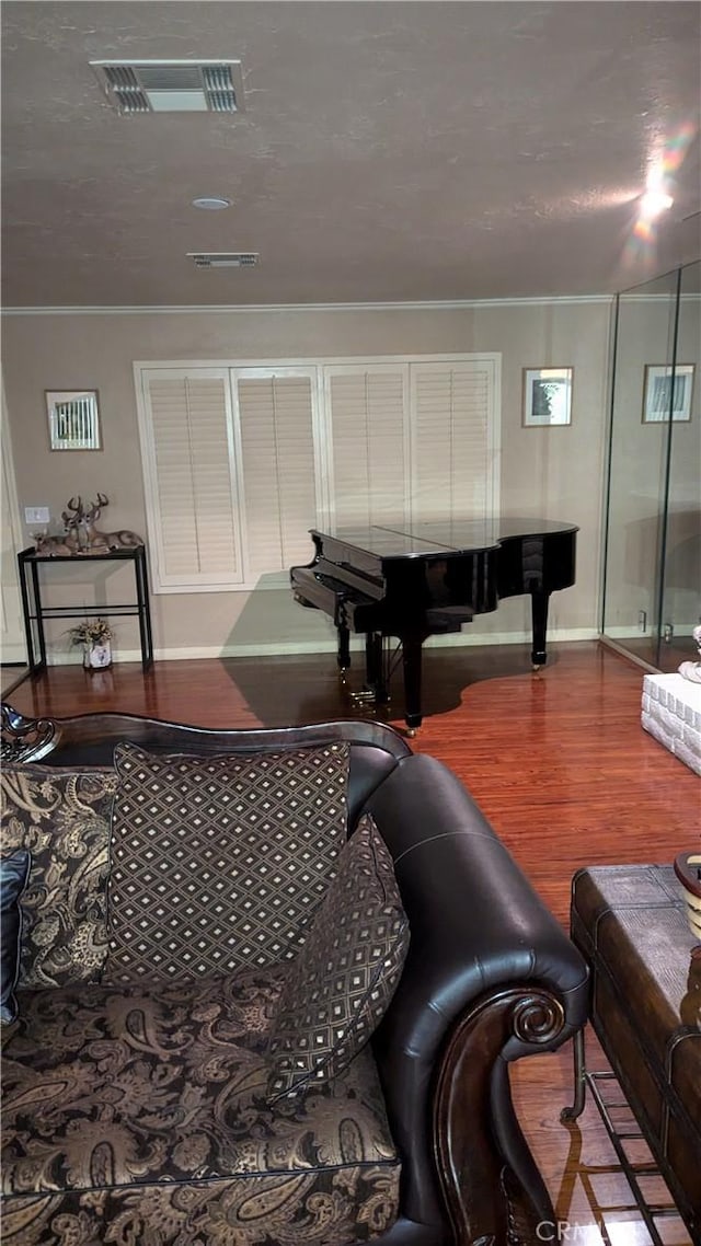 living room with wood-type flooring, a textured ceiling, and ornamental molding