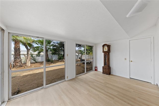 interior space featuring a wealth of natural light, vaulted ceiling, and light wood-type flooring