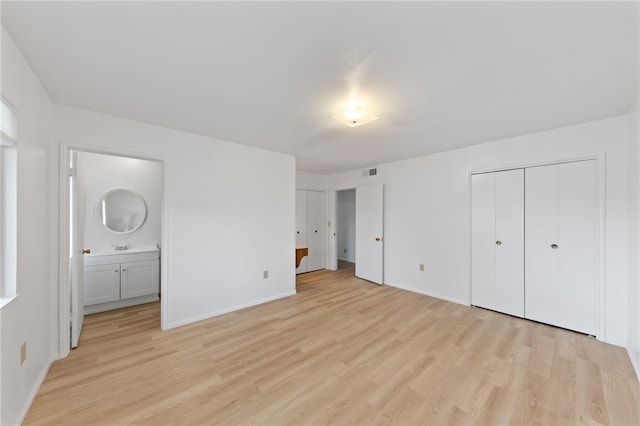 unfurnished bedroom featuring light hardwood / wood-style floors, ensuite bath, and a closet