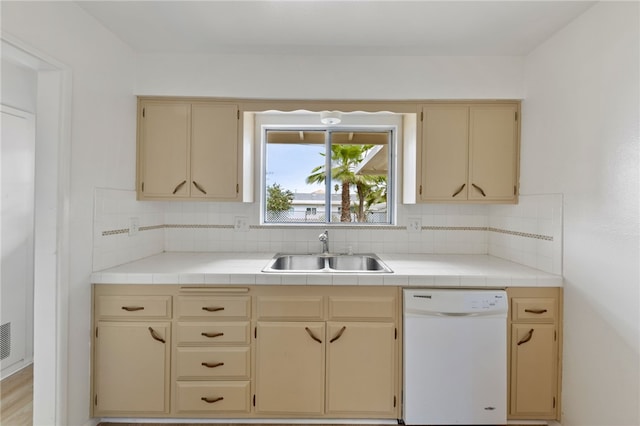 kitchen featuring tile counters, dishwasher, sink, backsplash, and light hardwood / wood-style floors