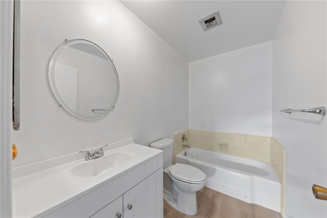 bathroom with hardwood / wood-style flooring, a bathtub, toilet, and vanity