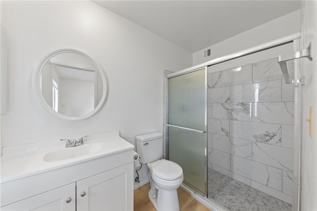 bathroom featuring hardwood / wood-style floors, vanity, a shower with shower door, and toilet