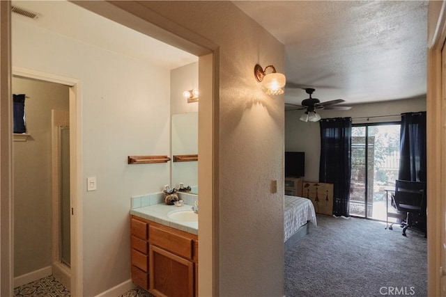 bathroom featuring a textured ceiling, vanity, ceiling fan, and walk in shower