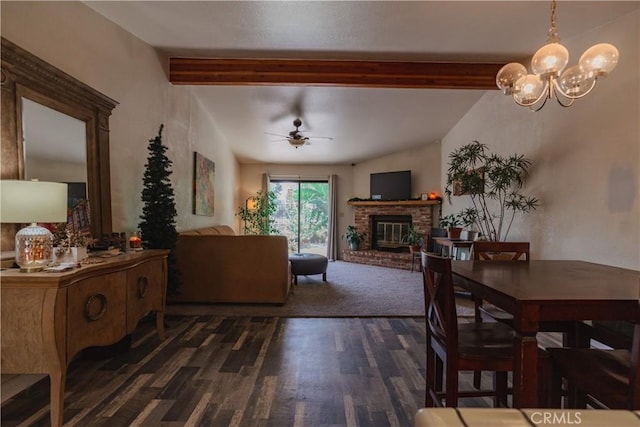 dining space with dark hardwood / wood-style flooring, lofted ceiling with beams, ceiling fan with notable chandelier, and a brick fireplace