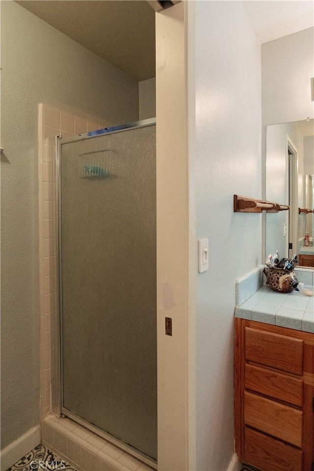 bathroom with tile patterned flooring, vanity, and walk in shower