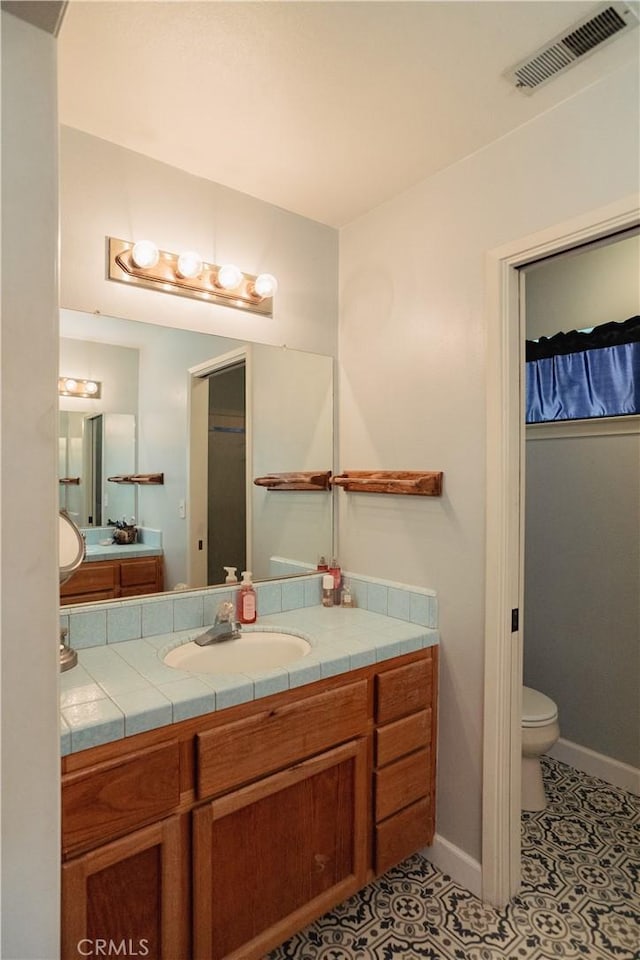 bathroom featuring tile patterned flooring, vanity, and toilet