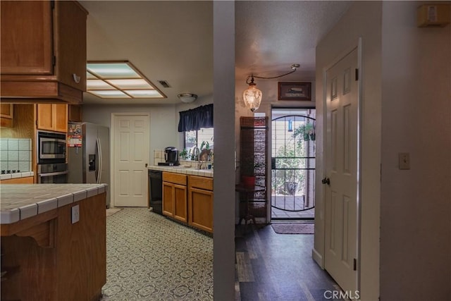 kitchen with tile countertops, dark hardwood / wood-style flooring, and stainless steel appliances